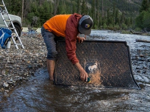 2024 Ford Bronco Sport close up view of man cleaning rubber mat in river