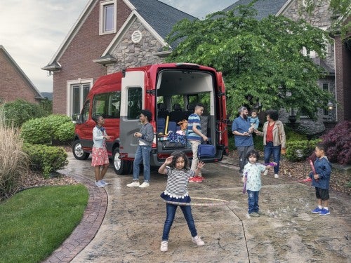 2024 Ford Transit parked outside a home with a large family outside vehicle, about to load up