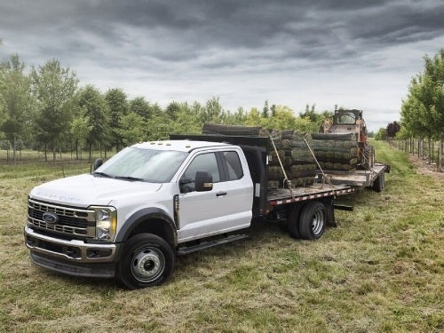 2024 Ford Chassis Cab towing two trailers of lumber and a tractor