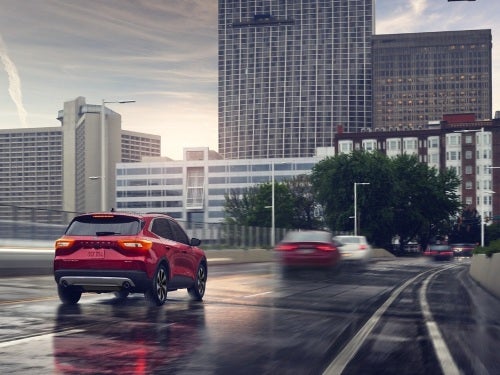 2024 Ford Escape Plug-in Hybrid driving into a city on a wet road
