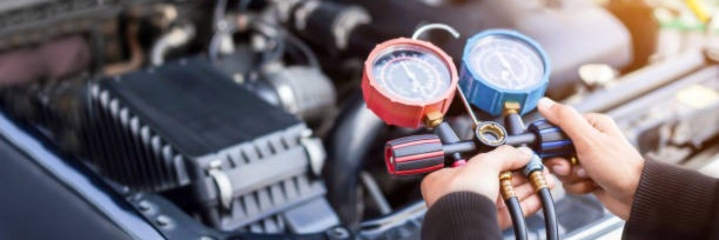 close up view of a service tech using gauges to test a vehicle's ac refrigerant