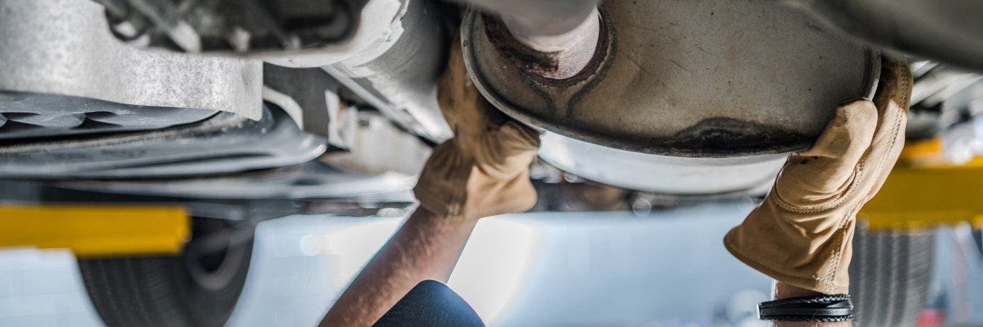 close up view of a service tech inspecting a catalytic converter